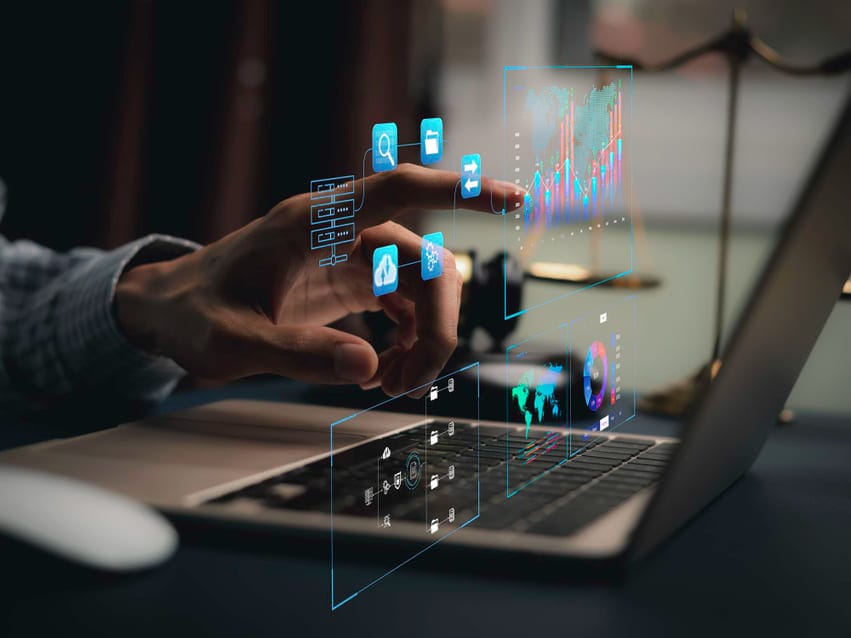 Mão interagindo com gráficos digitais flutuantes em um notebook, representando análise de dados em estratégias de marketing digital.