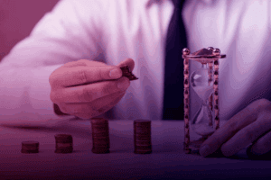 Empresário empilhando moedas ao lado de uma ampulheta, representando o cálculo do LTV (Lifetime Value) dos clientes.