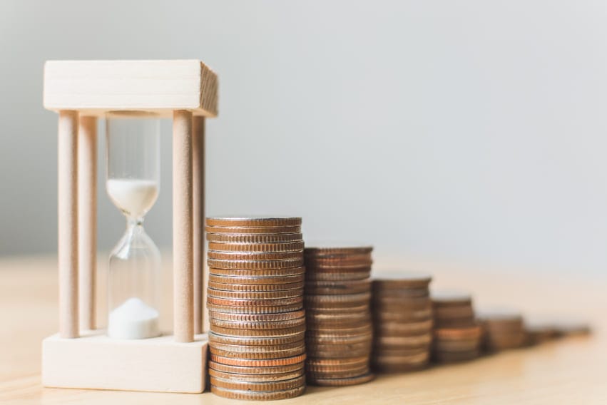 Pilhas de moedas em crescimento ao lado de uma ampulheta, simbolizando o valor de vida útil do cliente (LTV).