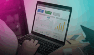 Pessoa usando notebook e celular enquanto ícones de cifrão flutuam, representando tráfego pago e marketing digital.