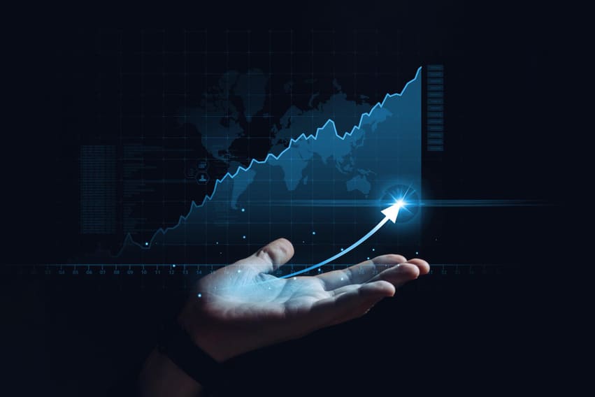 Mão segurando gráfico de crescimento com seta azul em ascensão, simbolizando sucesso e escalabilidade de negócios digitais.