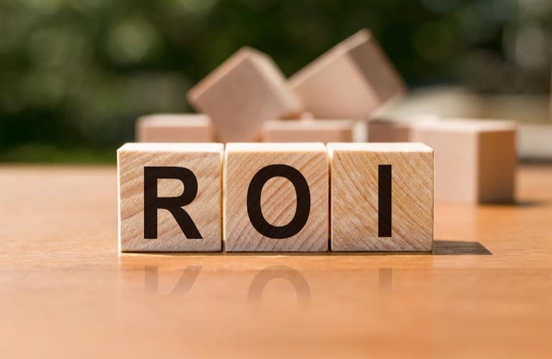 Blocos de madeira formando a palavra ROI sobre uma mesa, simbolizando o conceito de retorno sobre investimento de forma simples e direta.