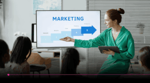 Profissional de marketing apresentando etapas de estratégia em tela para equipe, ilustrando o conceito de Marketing-Led Growth